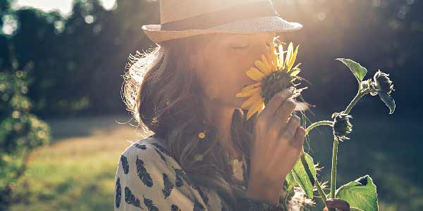 Young woman smelling a sunflower in the sunshine